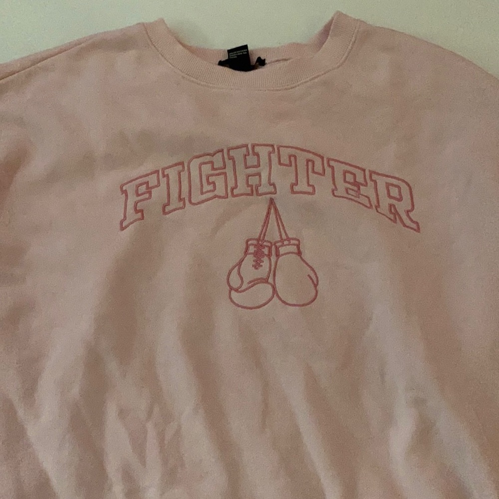 Pink crewneck that says fighter